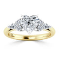 Gold ring with heart-shaped center diamond and four round side diamonds in a prong setting.