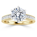 A gold ring with a large round diamond center stone and smaller diamonds set along the band.