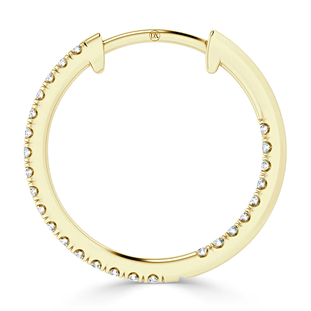A gold hoop earring is set with small, round white diamonds along its outer edge.