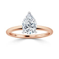 A rose gold ring with a pear-shaped diamond solitaire set in a simple, elegant band on a white background.