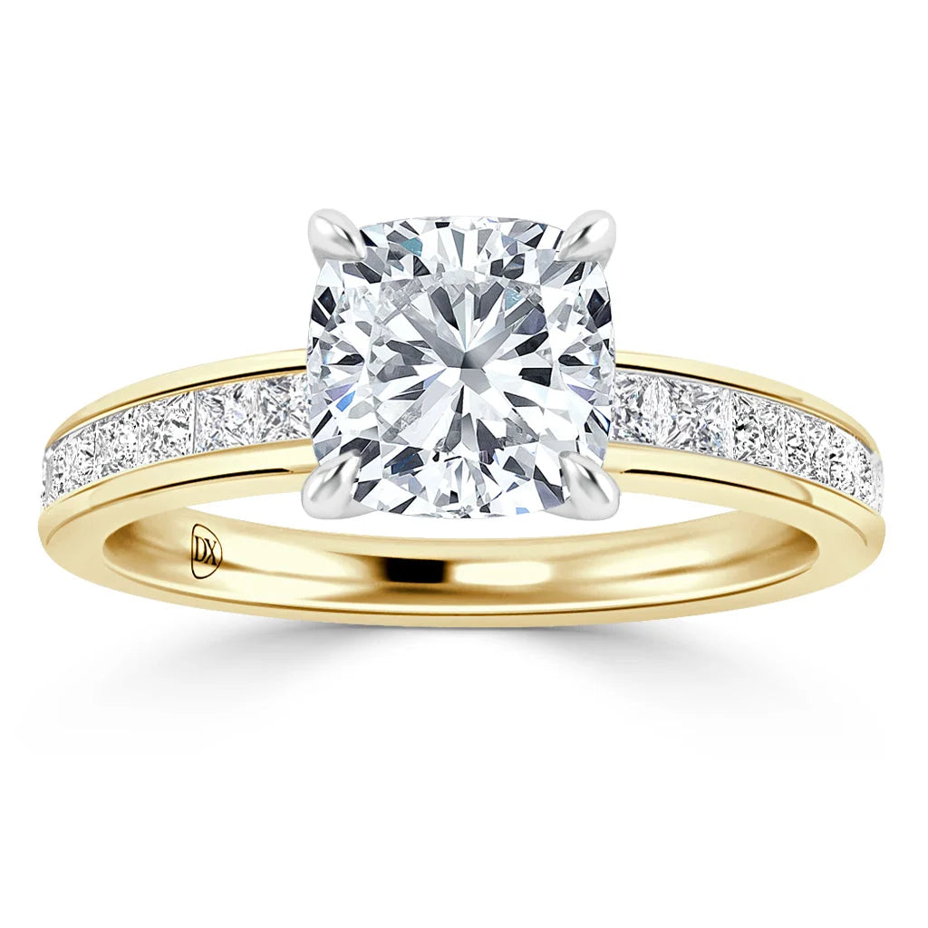 Gold ring with a cushion-cut diamond center stone and small diamonds set along the band, on white background.