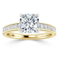 Gold ring with a cushion-cut diamond center stone and small diamonds set along the band, on white background.