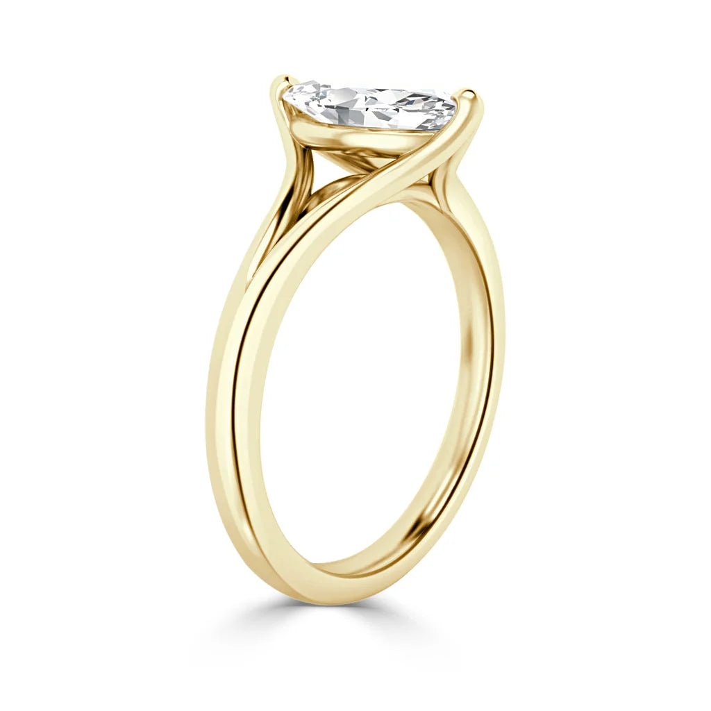 Gold ring with a thin band and a single oval diamond in a minimalist prong setting, viewed from the side.