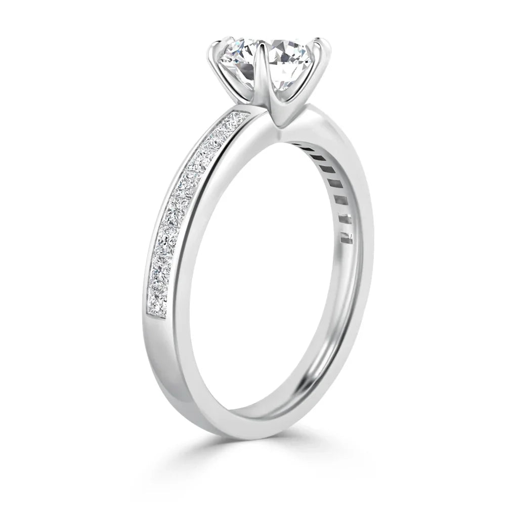A white gold ring with a round solitaire diamond and smaller diamonds set along the upper band.