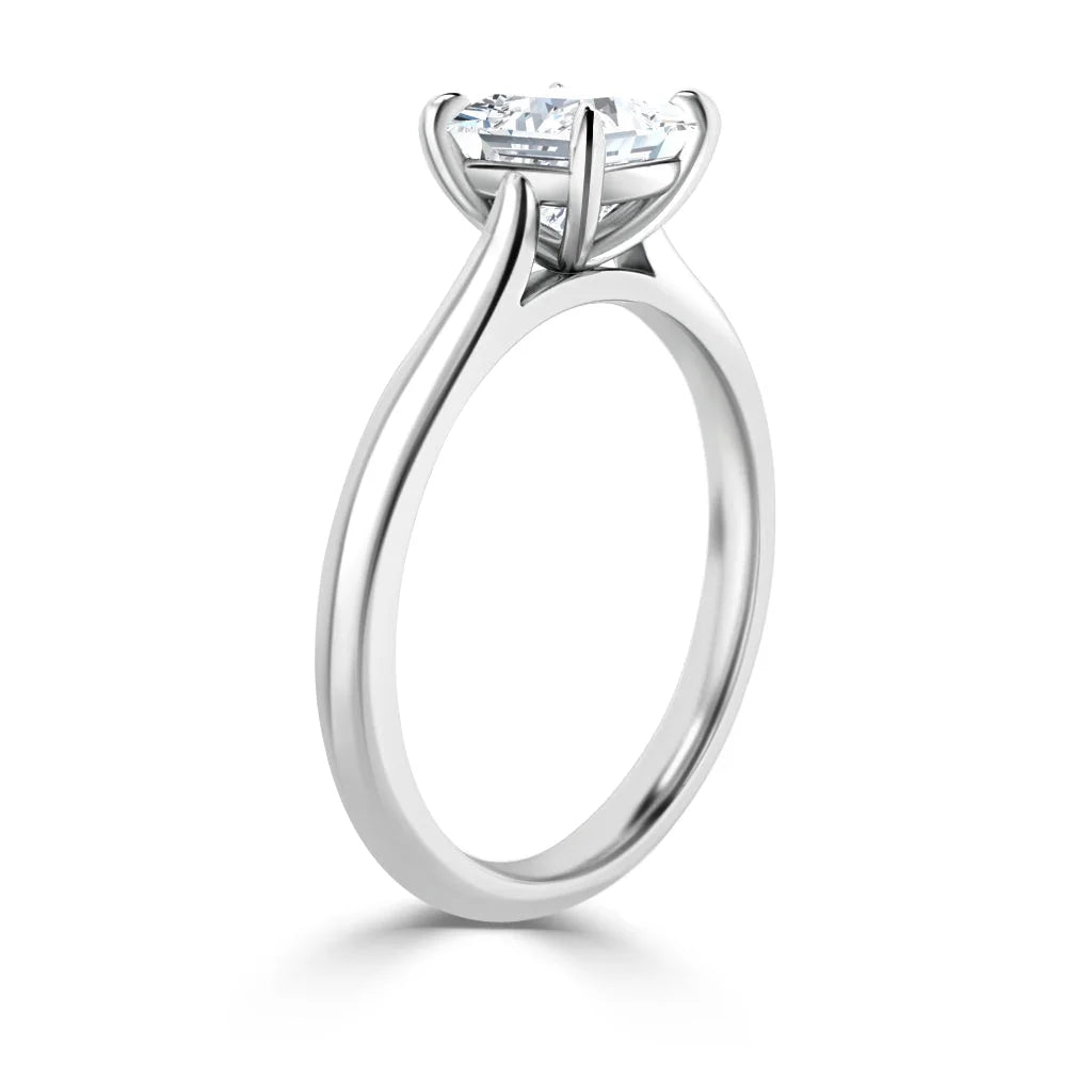 Side view of a solitaire engagement ring with a round diamond set in a sleek white metal band.