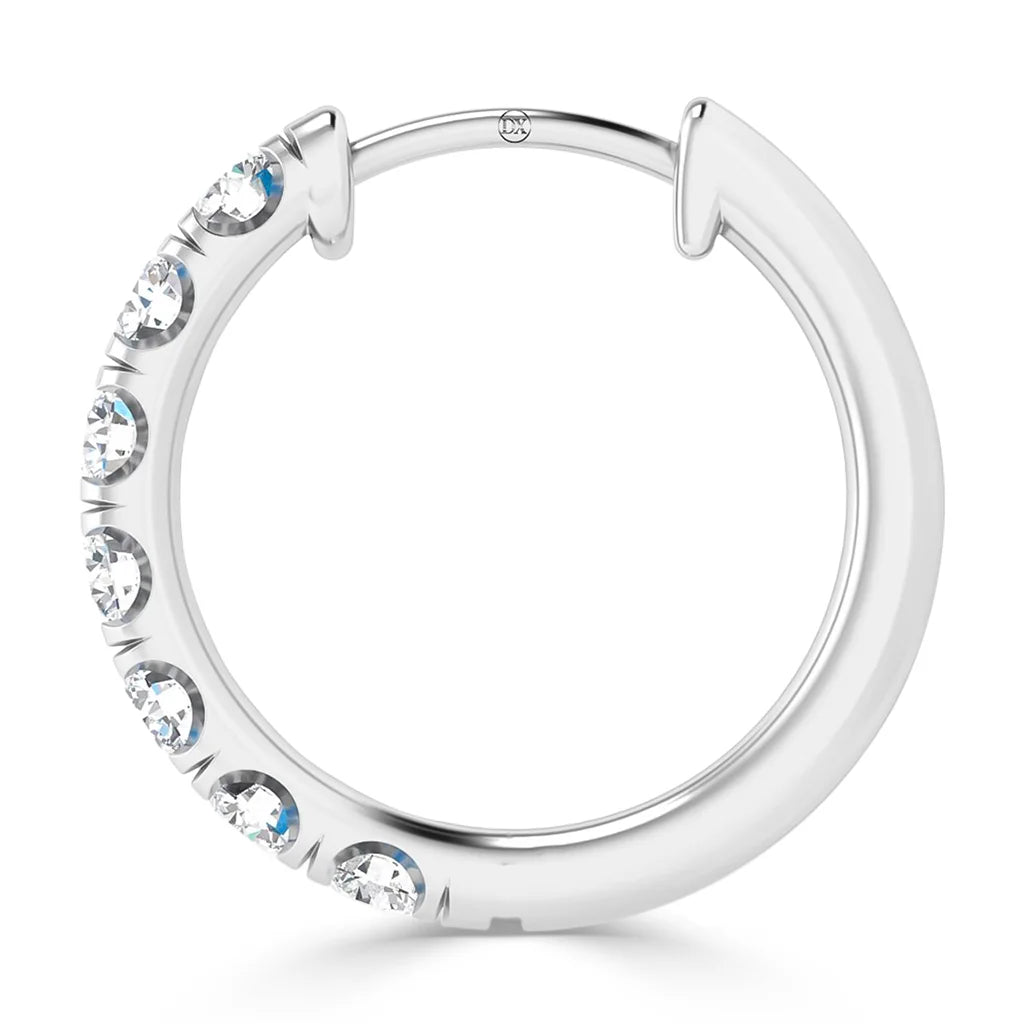 A silver hoop earring with seven round, clear gemstones embedded along one side.