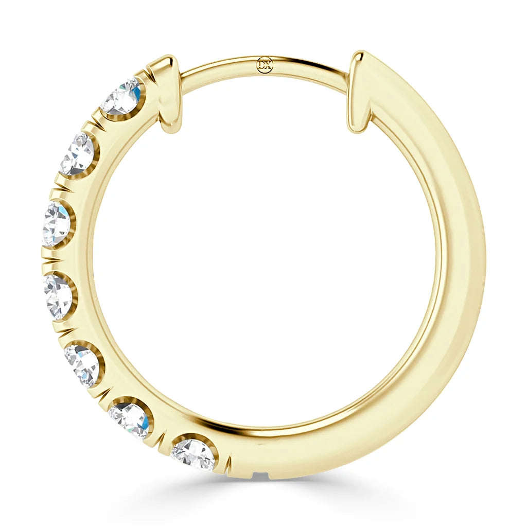 A gold hoop earring with seven round, clear gemstones set along one side in a row.