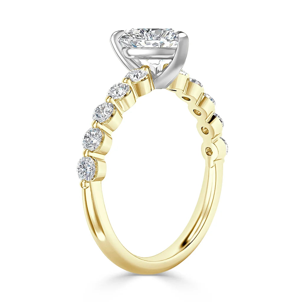 A yellow gold ring with round diamonds on the band and a large diamond in a white gold prong setting.