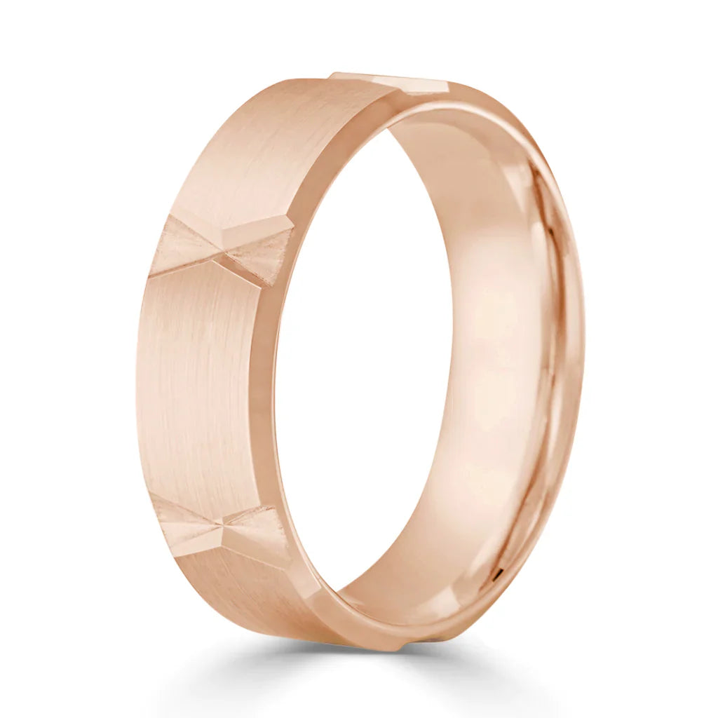A rose gold ring with a matte finish and repeating engraved bow-tie patterns around the band.