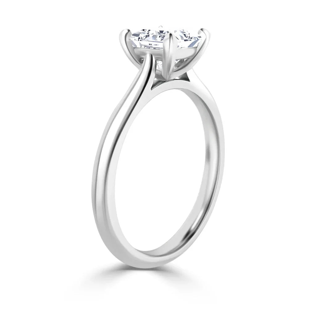 Side view of a simple platinum ring with a round, prong-set diamond solitaire on a polished band.