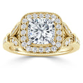 A gold ring with a cushion-cut diamond center, surrounded by a halo of smaller diamonds and ornate detailing.