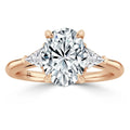Rose gold ring with a large oval diamond center and two triangular diamonds on each side.
