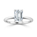 A solitaire emerald-cut diamond ring with a thin, polished white gold or platinum band.