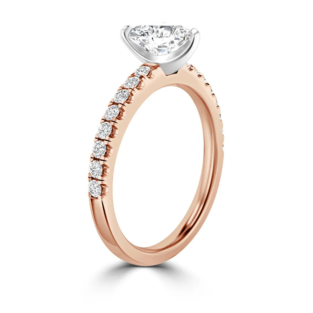 Rose gold ring with round solitaire diamond and small diamonds along the band, shown on a white background.