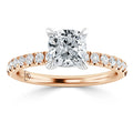 Cushion-cut diamond ring with a rose gold band and small diamonds set along the band, viewed from the front.
