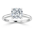 A silver ring with a cushion-cut diamond solitaire set in four prongs on a simple, polished band.