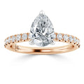 A pear-shaped diamond ring with a rose gold band adorned with small round diamonds.