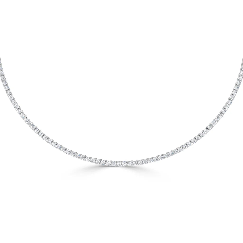A delicate, thin diamond tennis necklace with evenly spaced round diamonds on a white background.