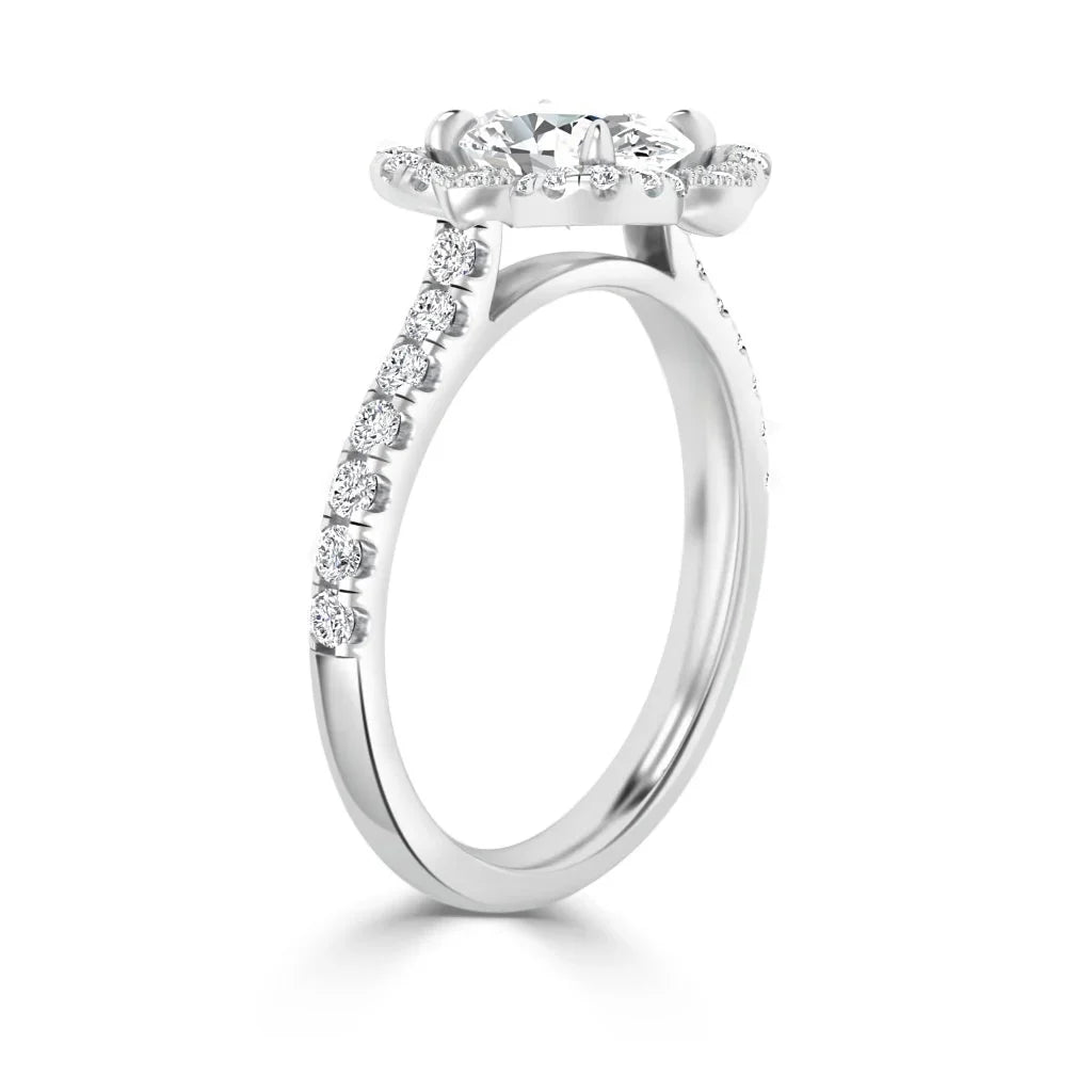 White gold ring with round diamond halo setting and diamonds along the band, viewed from an angle.