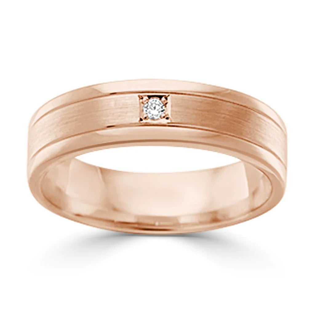A rose gold ring with a small, square-set diamond centered on a matte band with polished edges.