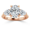 A rose gold ring with an oval diamond center and two round side diamonds on a polished band.