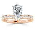 Rose gold ring with a pear-shaped diamond center and round diamonds set along the band.