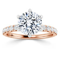 Rose gold ring with a large round diamond center and smaller diamonds along the band, prong setting.