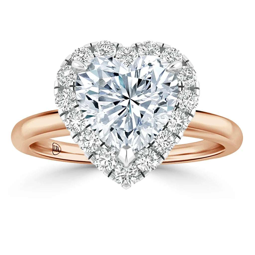 Heart-shaped diamond ring with a halo of smaller diamonds on a rose gold band, shown on a white background.