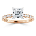 A rose gold ring with a square-cut diamond center stone and small diamonds on the band.