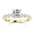 A gold ring with a large cushion-cut center diamond and seven smaller round diamonds on each side of the band.