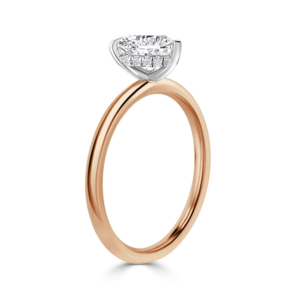 A rose gold ring with a round, brilliant-cut diamond set in a white gold prong setting, shown side view.