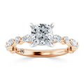 A rose gold ring with a cushion-cut center diamond and marquise side diamonds on the band.