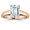 Emerald-cut diamond solitaire ring with a rose gold band and four prongs holding the stone.