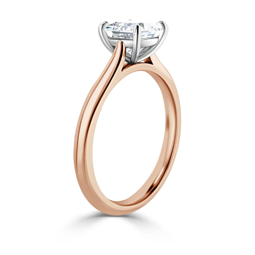 Rose gold solitaire ring with a round diamond in a white gold four-prong setting, shown from the side.