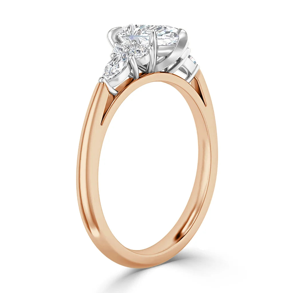 A rose gold ring with a pear-shaped diamond and two smaller round diamonds in a white gold setting.