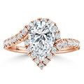 A rose gold ring with a pear-shaped diamond center, halo setting, and diamond-accented band.