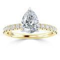 A gold ring with a large pear-shaped diamond center and small round diamonds on the band.