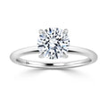 A round solitaire diamond ring with a thin, polished white gold band and four-prong setting.