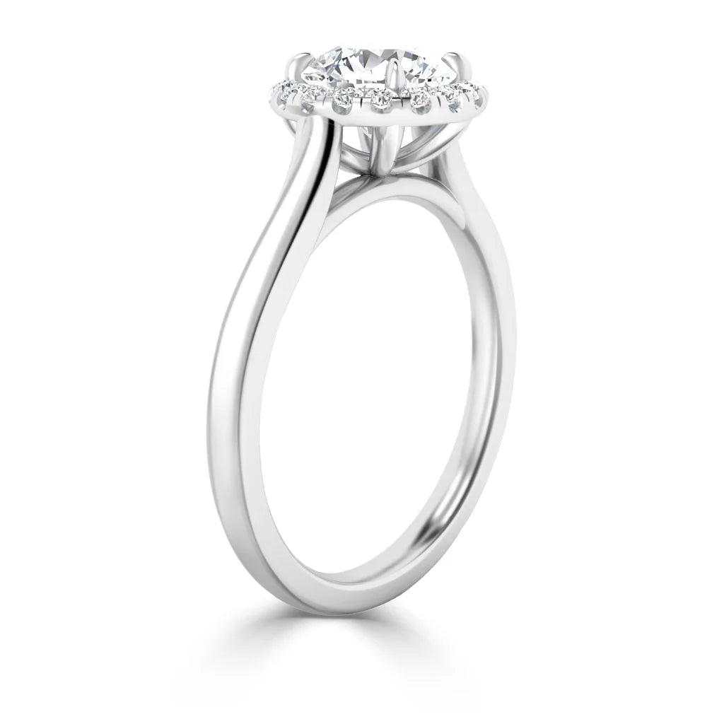 A silver ring with a round center diamond and a halo of smaller diamonds, shown from a side angle.