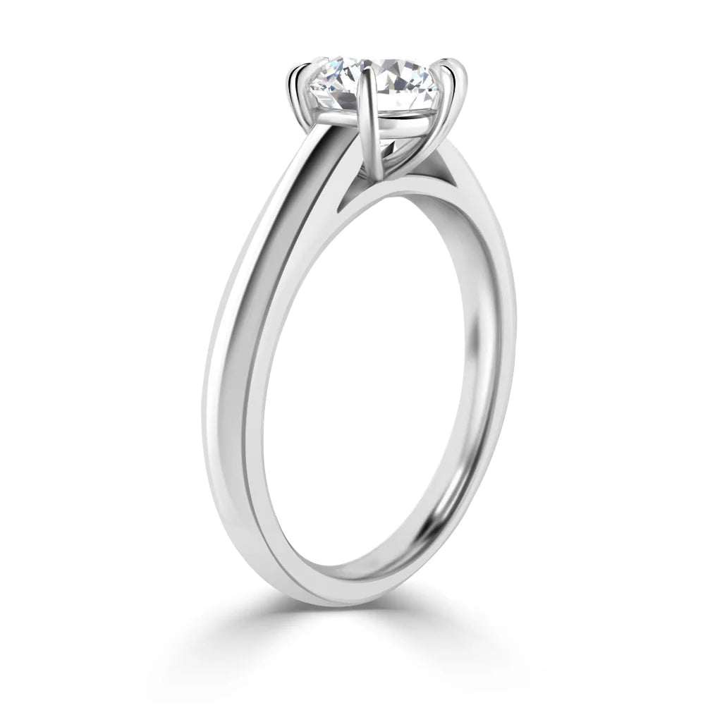A close-up side view of a silver solitaire ring with a round, prong-set diamond on a plain metal band.