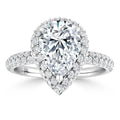 Pear-shaped diamond ring with a double halo and pavé diamond band, set in white gold, on a white background.