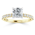 Gold ring with a cushion-cut diamond center and small diamonds along the band, shown on a white background.