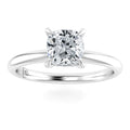 A silver engagement ring with a cushion-cut diamond solitaire set in four prongs on a plain band.