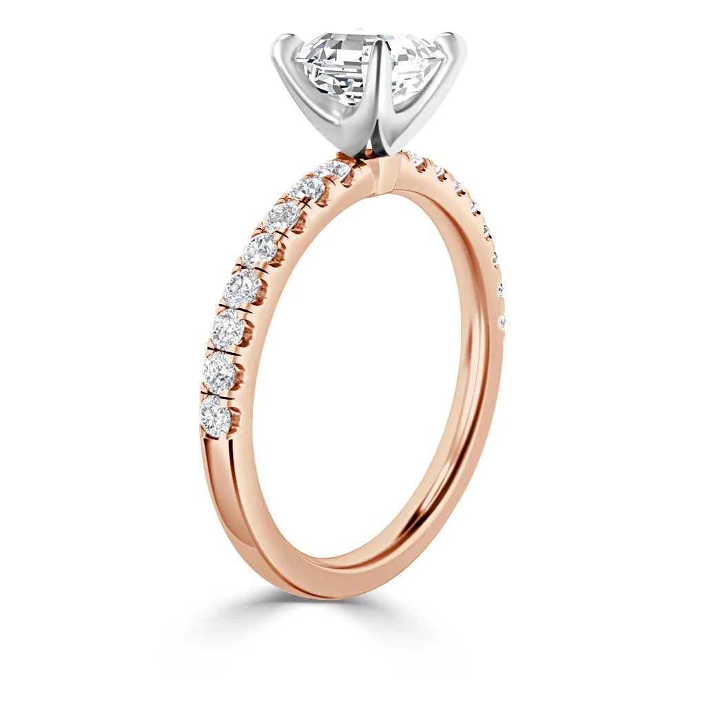 Rose gold ring with a large solitaire diamond and small diamonds set along the thin band, shown in profile view.