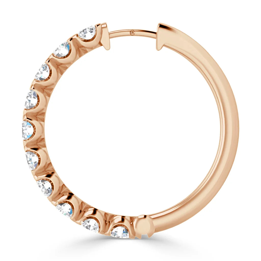 A rose gold hoop earring with white gemstones embedded along half of its outer edge.