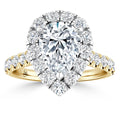 A pear-shaped diamond ring with a gold band, surrounded by a halo and band of round white diamonds.