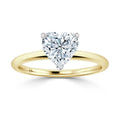 A gold ring with a heart-shaped diamond solitaire set in a prong setting on a plain gold band.