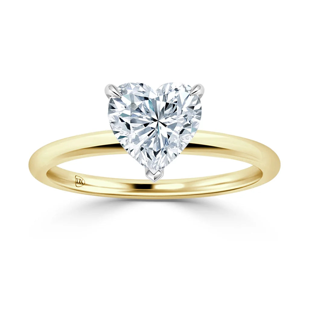 A gold ring with a heart-shaped diamond solitaire set in a prong setting on a plain gold band.