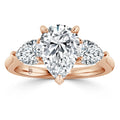 Rose gold ring with a pear-shaped center diamond flanked by two smaller pear-shaped diamonds.