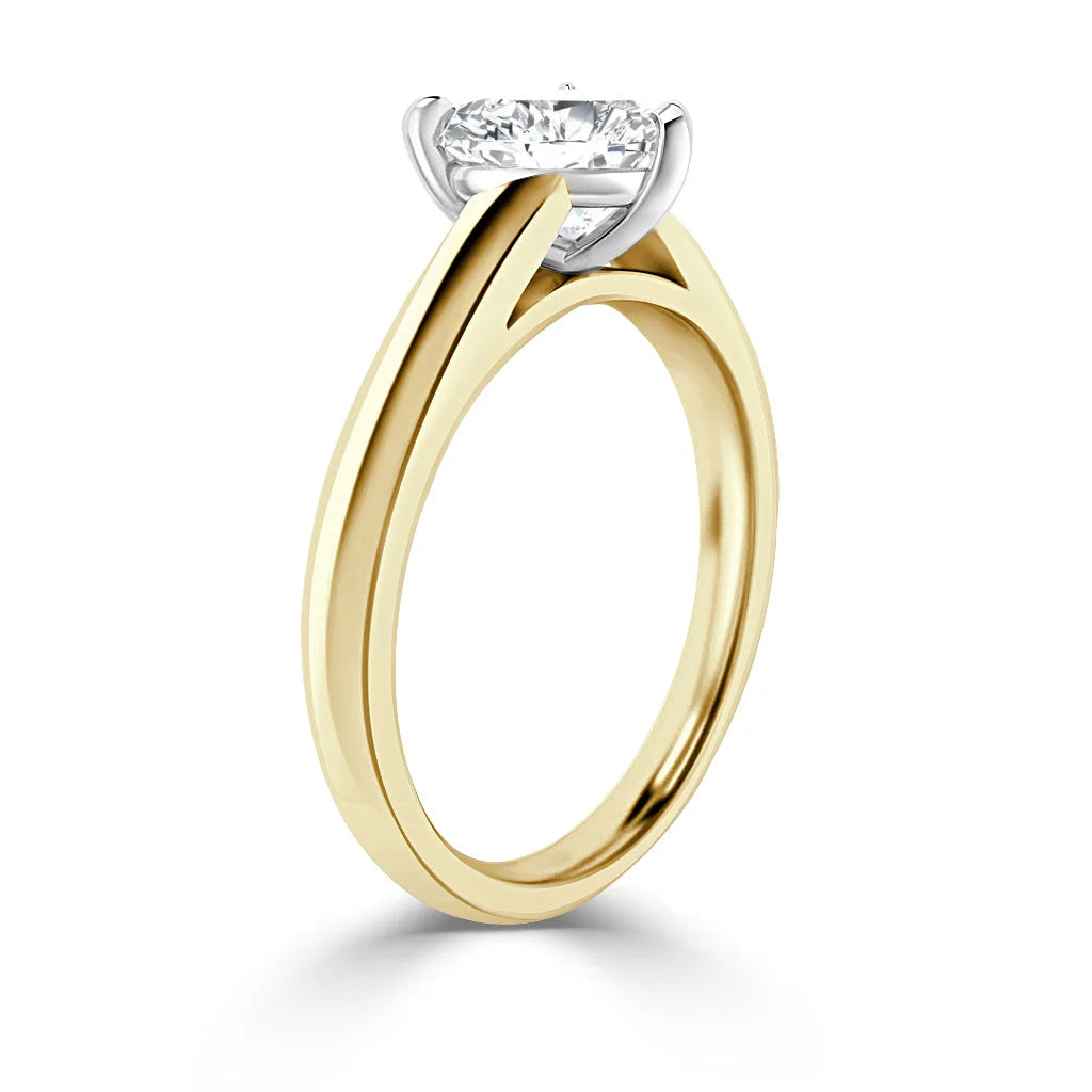 Gold band solitaire ring with a round, prong-set diamond viewed from an angle on a white background.